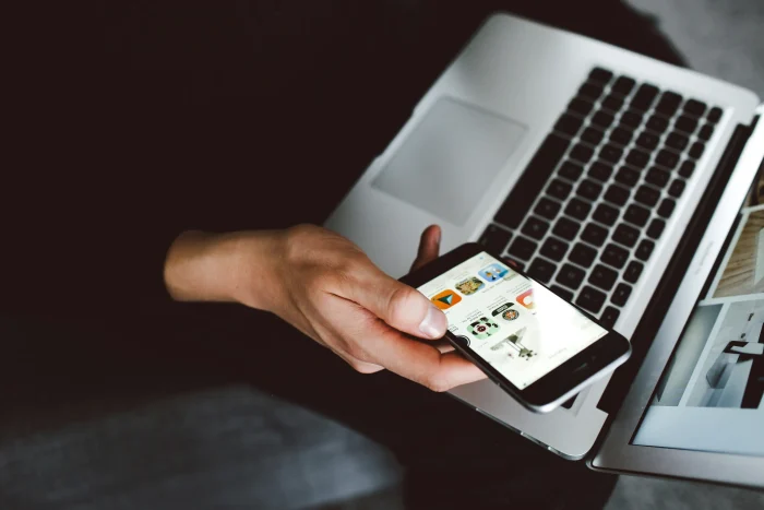 person using a laptop and holding a phone